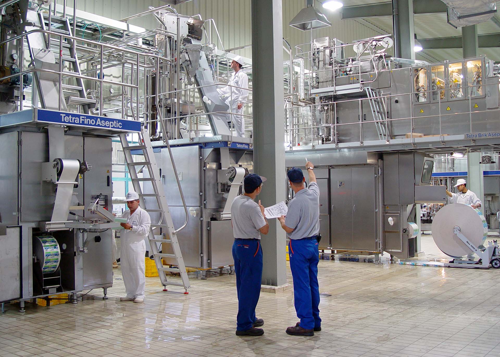 Team inspecting Tetra Pak processing equipment in an industrial setting.